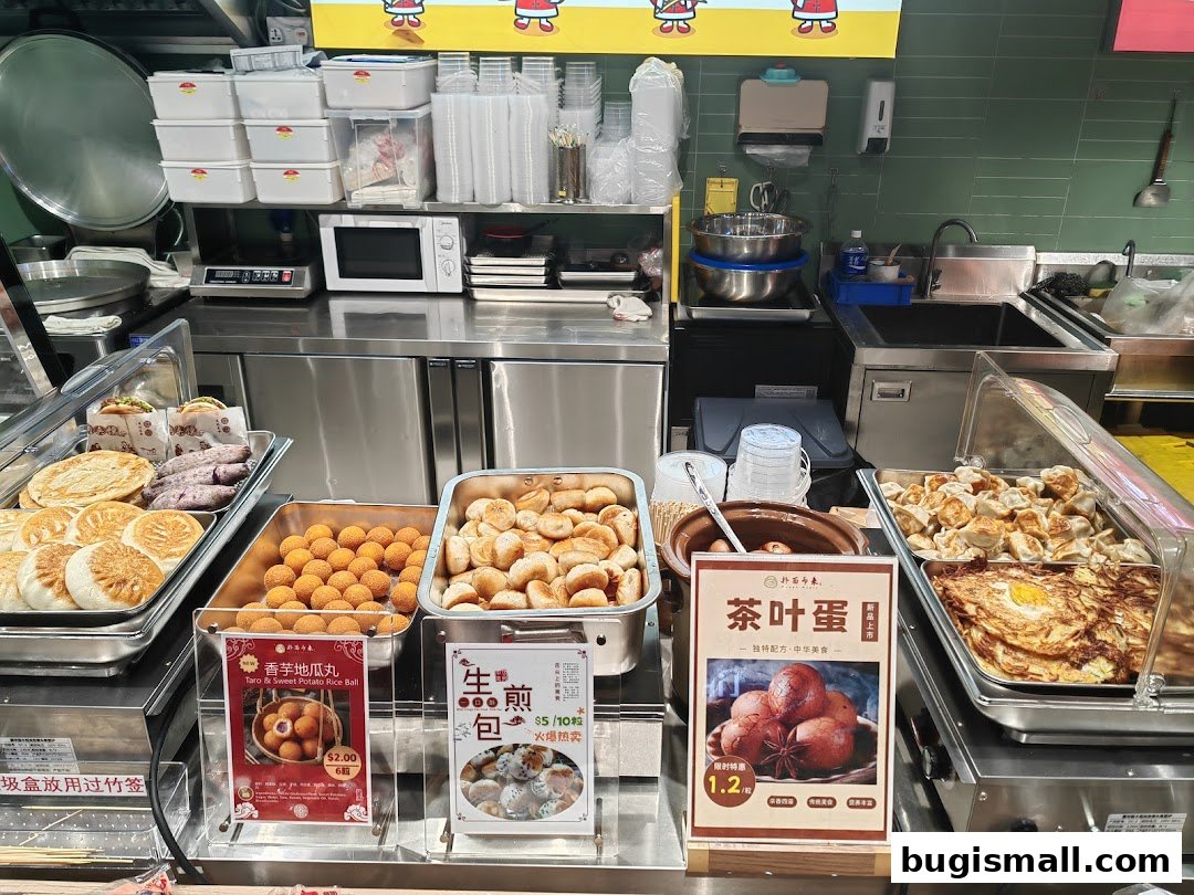 A food stall display featuring various Chinese snacks like dumplings, buns, and sweet potato balls.