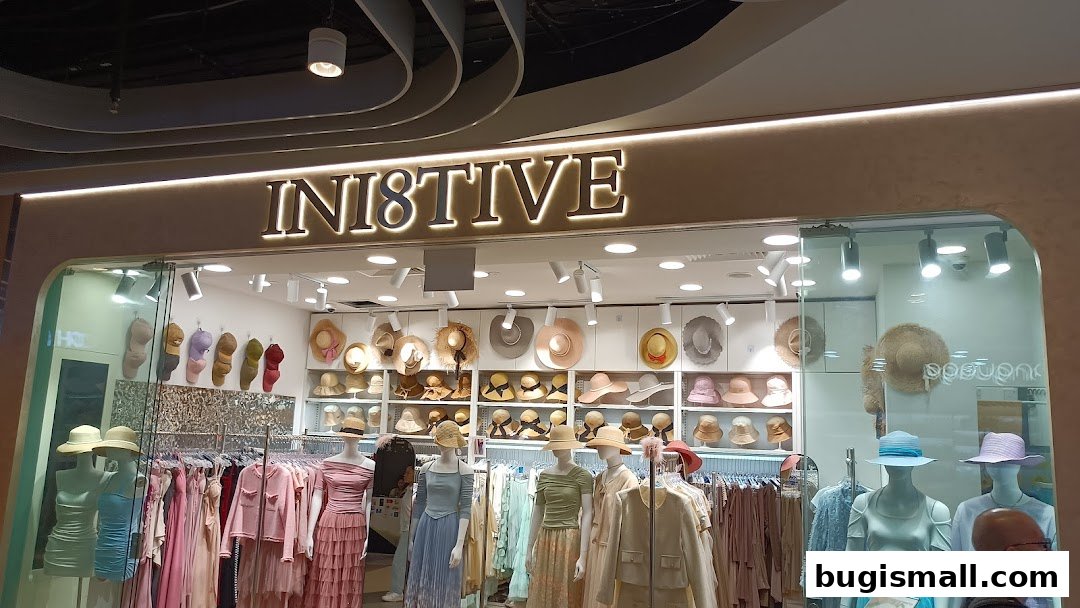 A fashion boutique named INI8TIVE displaying hats and women's clothing on mannequins and racks.